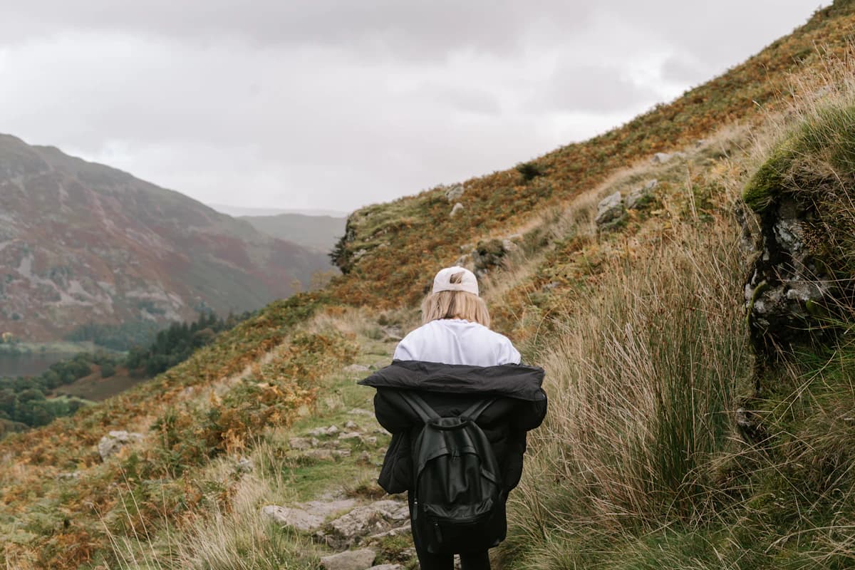 A person walking on a quiet mountain trail, shown as representative lifestyle imagery